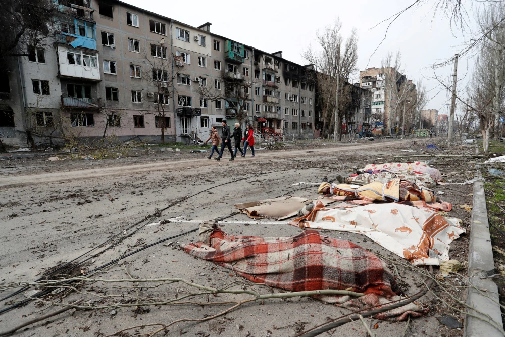 Na ulicama Mariupolja, skupine tijela poredane su ispod šarenih deka, okružene polomljenim drvećem i spaljenim zgradama., Foto: Alexander Ermochenko/Reuters